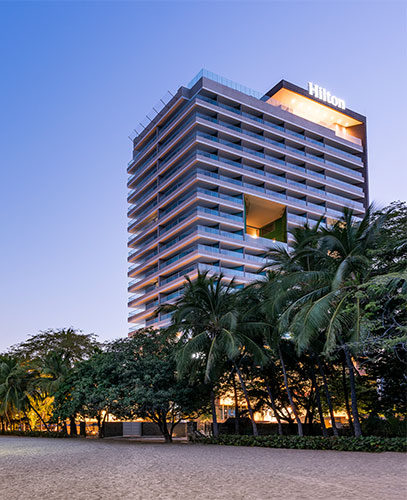 Fachada del hotel Hilton Santa Marta al atardecer rodeado de palmeras