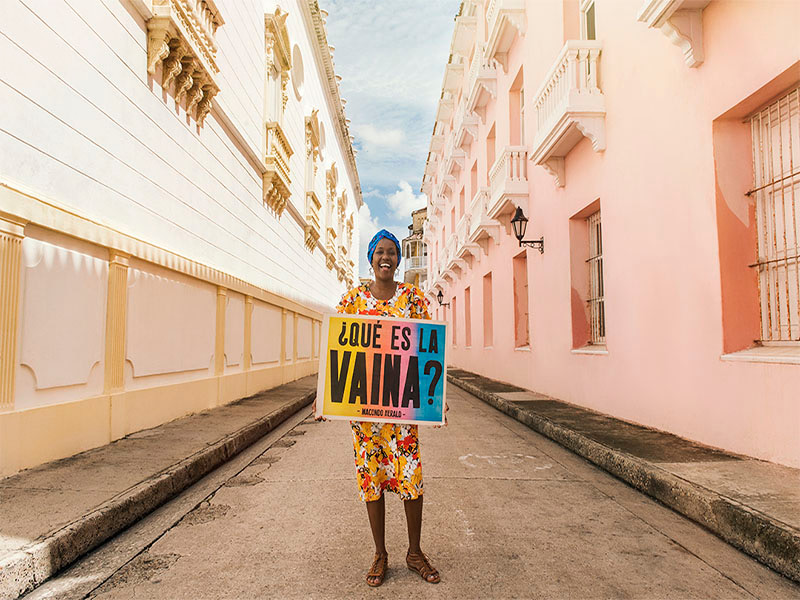 A black woman holding a poster that reads “¿Qué es la vaina?”
