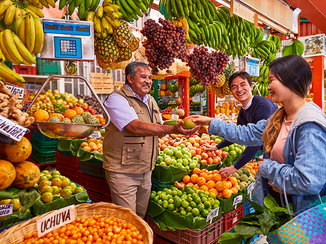 marquet place full of fruit where vendor sells mango to tourists.