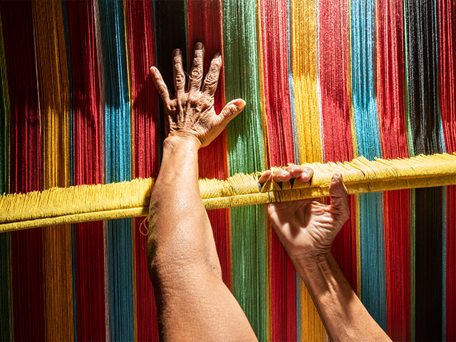 A woman’s hand working with colorful thread.