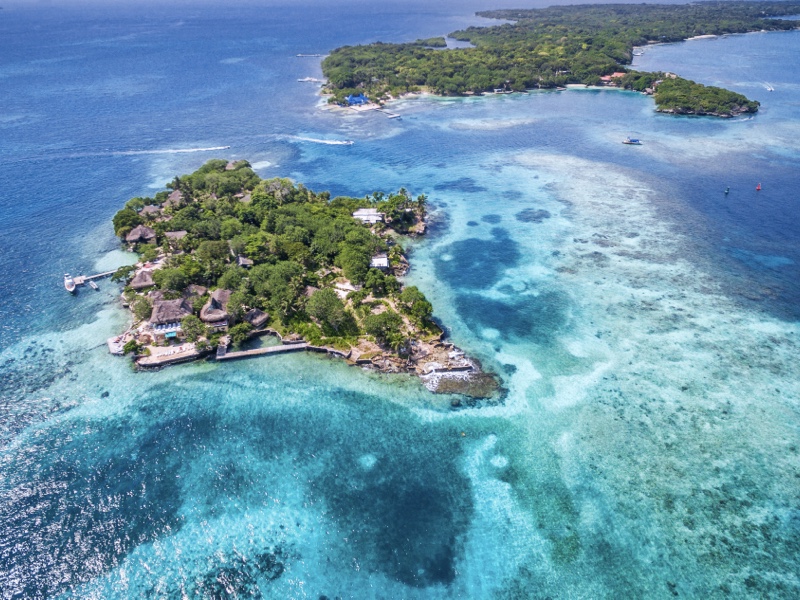 Una vista aérea de las Islas del Rosario, rodeadas de un mar de diversos colores. Anímate a vivir un retiro espiritual en este lugar.