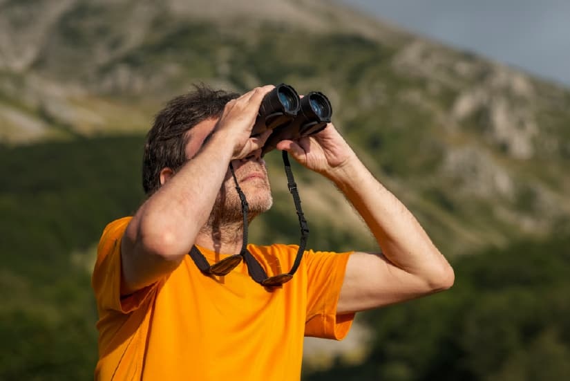 Homem observando aves com a ajuda de binóculos
