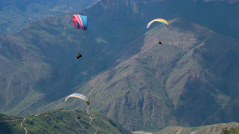 People doing paragliding in the Chicamocha canyon. A place that can be enjoyed by a business traveler.