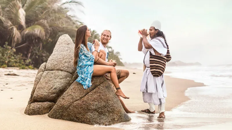 Two tourists listen to the music of a native from the Sierra Nevada de Santa Marta. This city is part of the García Márquez route in the Colombian Caribbean