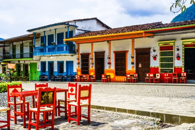 Мужчина идет по красочным улицам Jardín, Antioquia